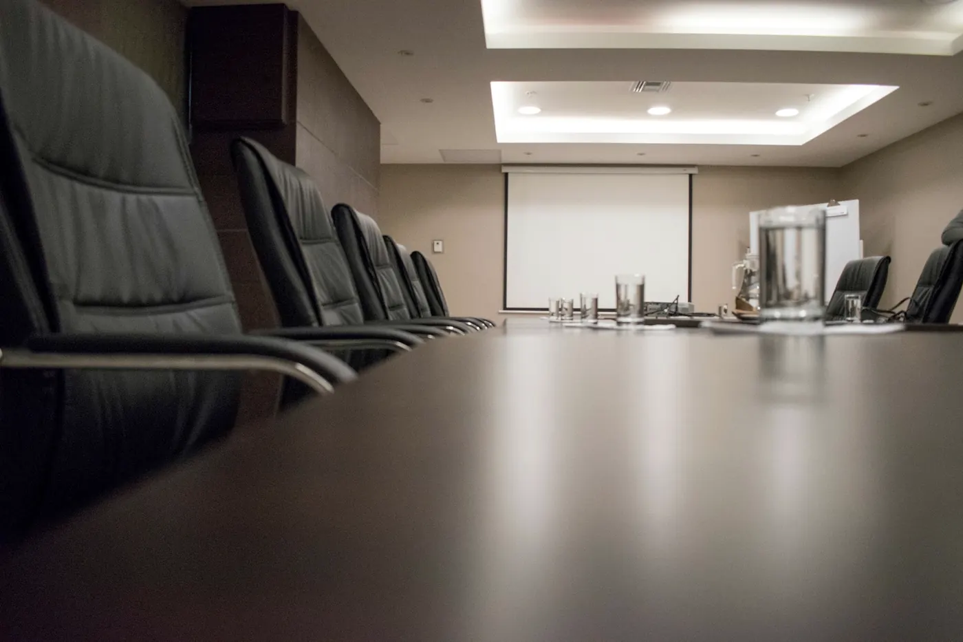 An empty boardroom with a long table and leather chairs.