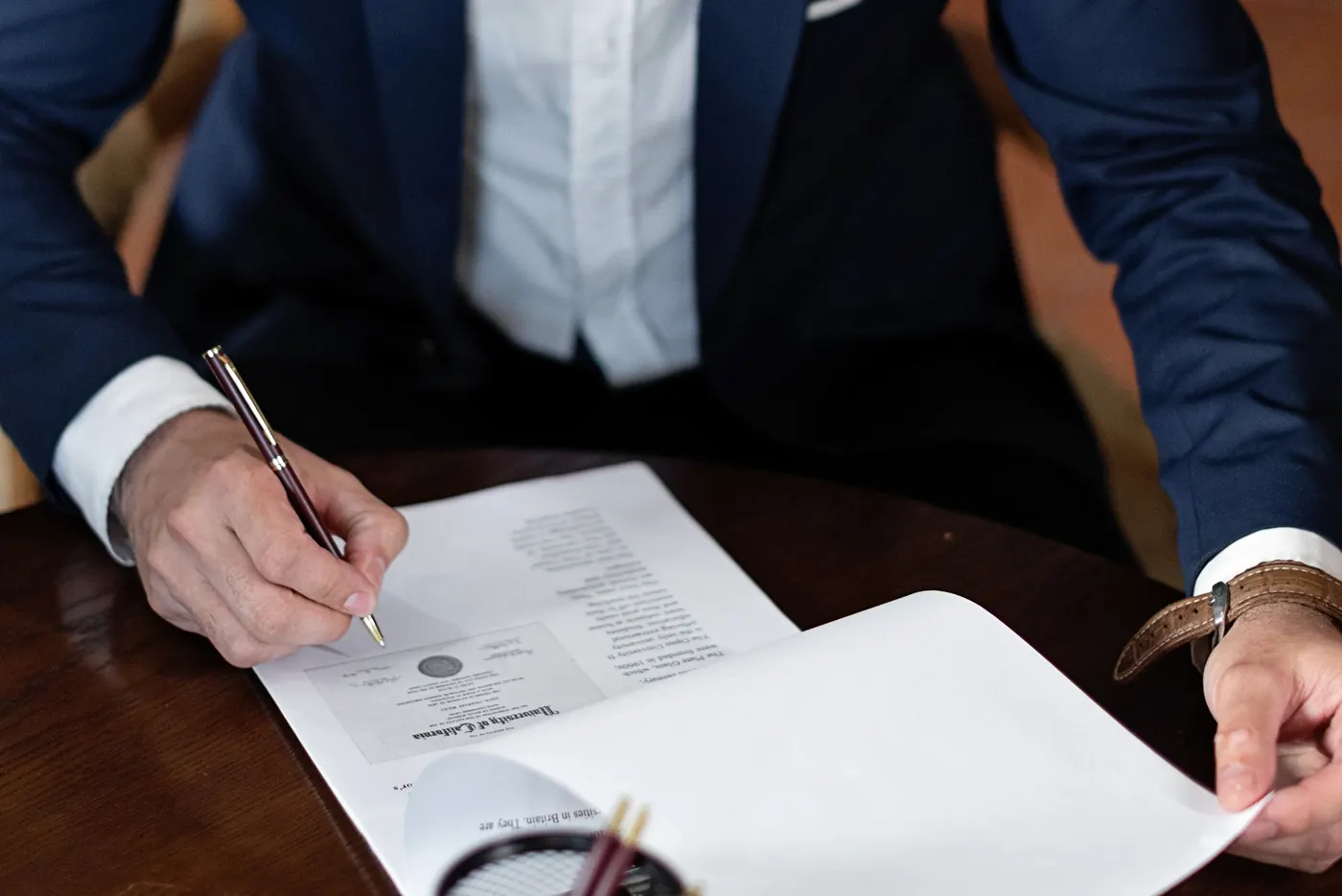 A professional signing documents at a desk.