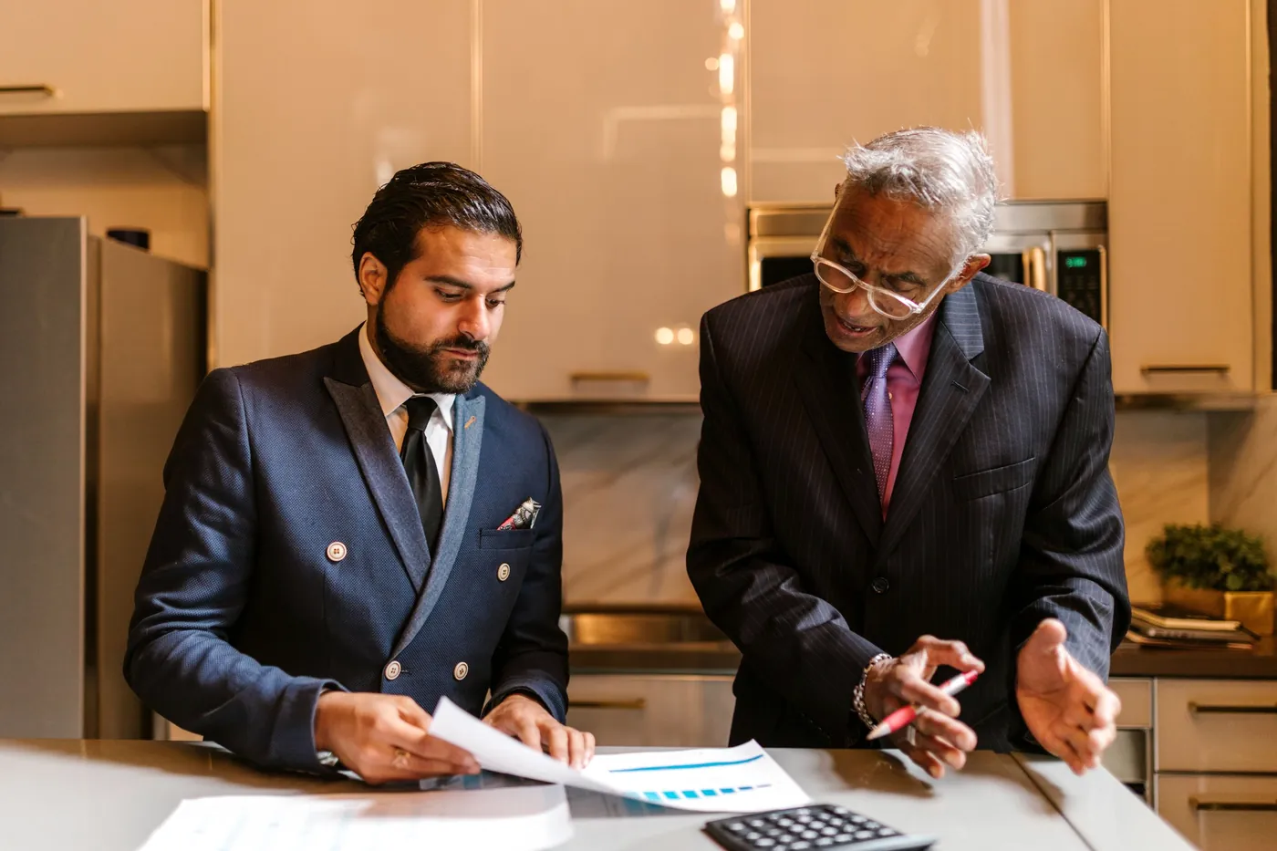 Two businessmen reviewing financial documents together at a desk.