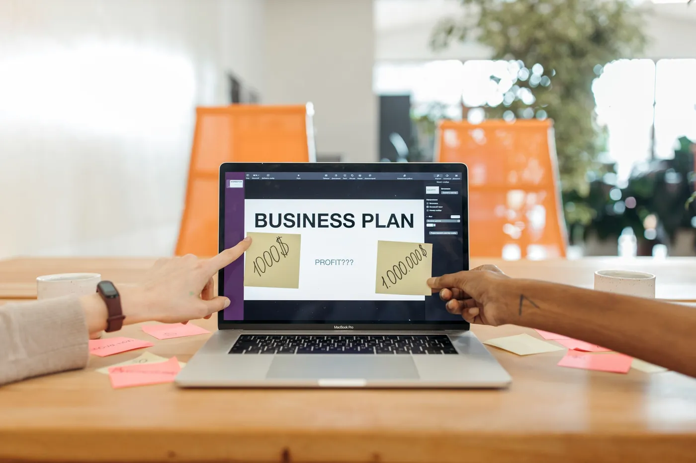 A laptop showing a business plan on a desk with sticky notes.