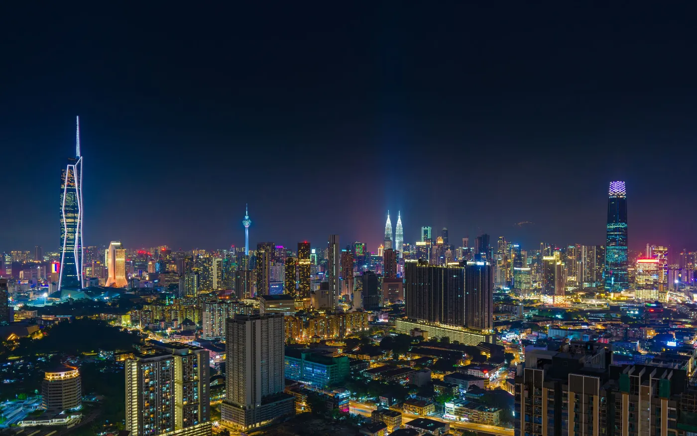 The Kuala Lumpur skyline at night with the KL Tower lit up.